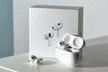 White wireless earbuds with charging case on a light gray surface